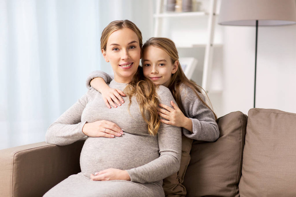 happy pregnant woman and girl hugging at home - Foto, Imagen
