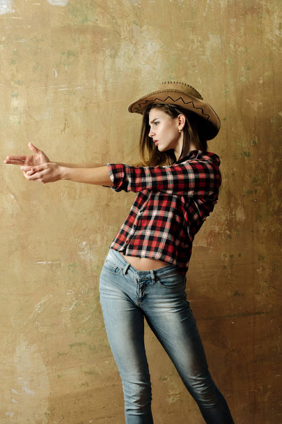 Pretty girl in stylish cowboy hat showing finger gun - Foto, Imagem