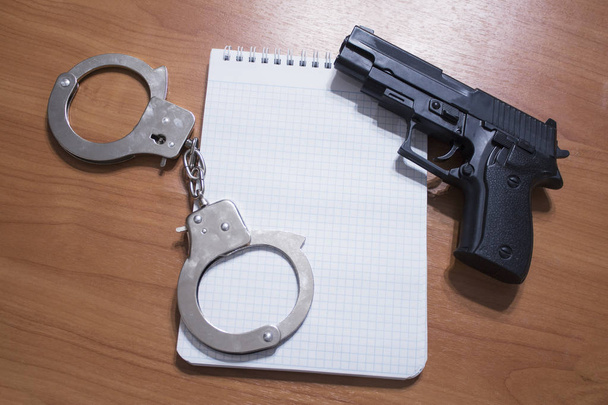 Handgun handcuffs and notepad on the table with copy space - Photo, Image