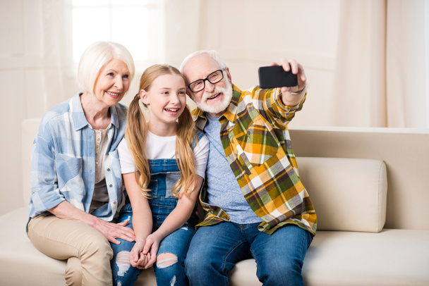 Tyttö isovanhempien kanssa ottaen selfie
 - Valokuva, kuva