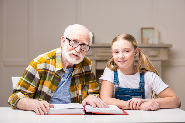 Grandfather with girl reading book - Foto, imagen
