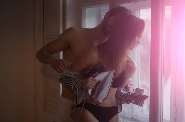 sexy girl with iron, coffee cup and man at window - 写真・画像