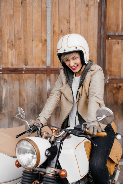 Hymyilevä tyttö moottoripyörällä. Moottoripyöräilijät. Valkoinen moottoripyörä sivuvaunulla
. - Valokuva, kuva