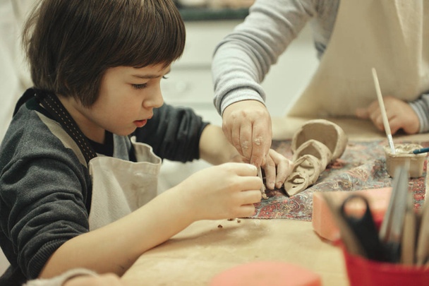 Il bambino è impegnato in una scuola di ceramica, scolpisce un prodotto di argilla
 - Foto, immagini