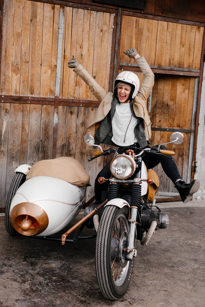 Lachende meisje op een motorfiets. Gelukkig meisje toont emoties. Motorfiets kaferacers. Witte motorfiets met een grote zijspan. Het meisje schreeuwt gelukkig - Foto, afbeelding