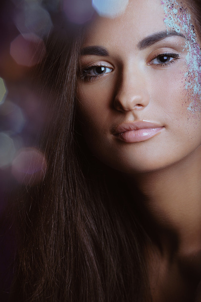 Beautiful woman with festive makeup in color spray and boke lights - Photo, Image