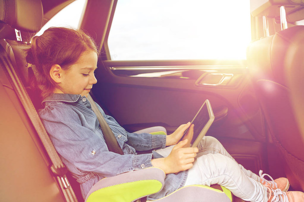 happy little girl with tablet pc driving in car - Photo, Image