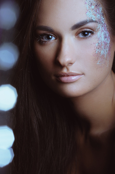 Hermosa mujer con maquillaje festivo en polvo de pulverización de color y luces de arco
 - Foto, imagen