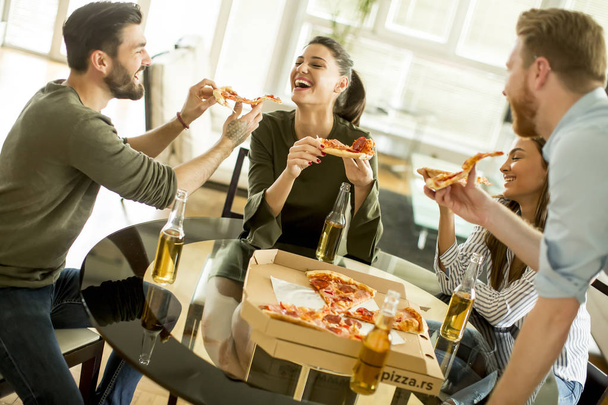 Друзья едят пиццу в современном интерьере
 - Фото, изображение