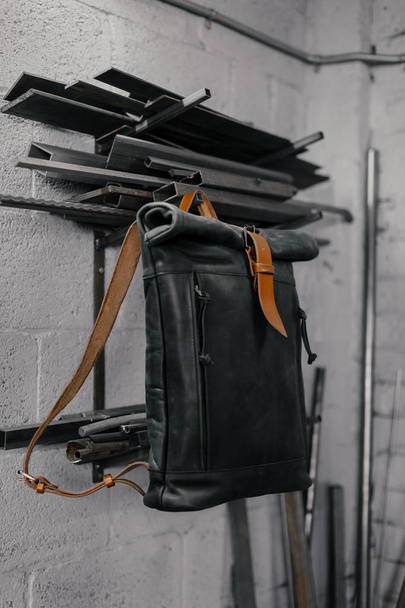 Exclusive black leather backpack. Backpack near the wall. The tools in the garage. Metal pipes near the wall - Fotoğraf, Görsel