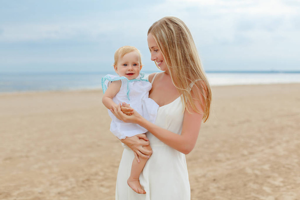 Mom and little charming little girl baby  on the beach in summer - Photo, image