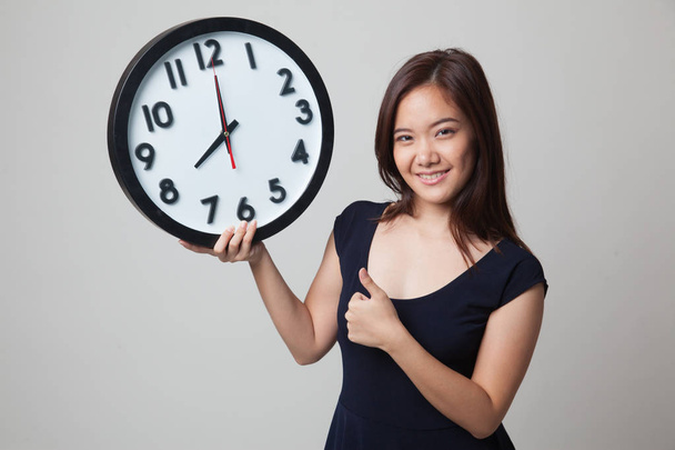 Young Asian woman thumbs up with a clock. - Fotoğraf, Görsel