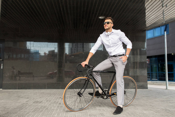 man with bicycle and headphones on city street - Fotó, kép