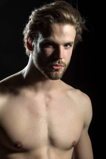 Naked man looking at the camera on black background in the studio closeup. Handsome man - Фото, зображення