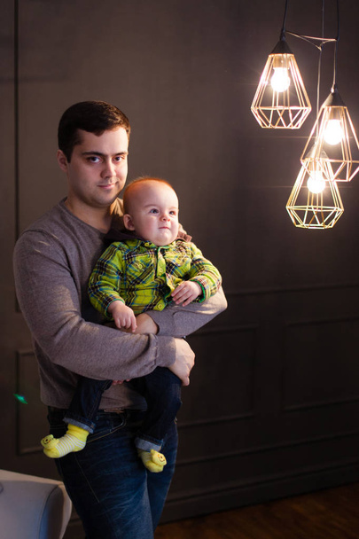 Pai abraçar seu filho ao lado de uma lâmpada na forma de lâmpadas, chave baixa, famyly
 - Foto, Imagem