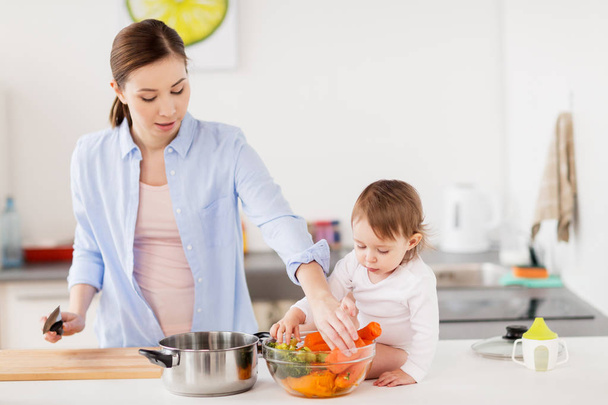 happy mother and baby cooking food at home kitchen - Фото, зображення