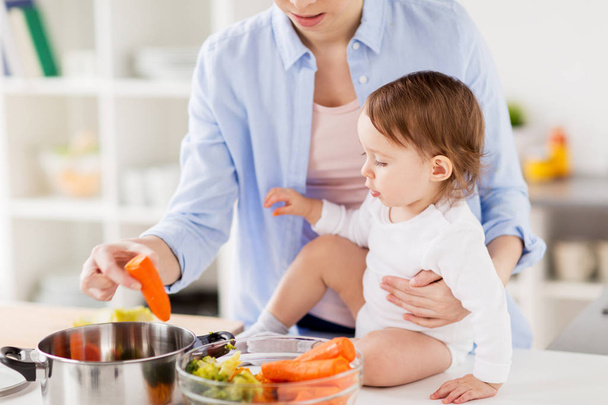 happy mother and baby cooking vegetables at home - Fotoğraf, Görsel