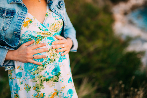 Pregnant woman holding belly with hands - Foto, afbeelding