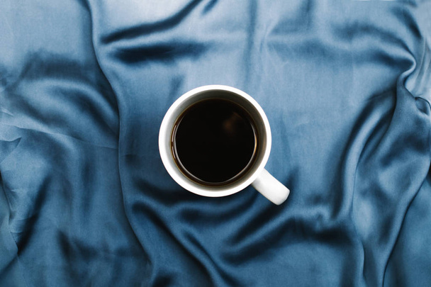White mug on blue cloth - Φωτογραφία, εικόνα