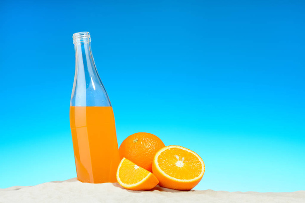 La botella de zumo de naranja y frutas en la playa
 - Foto, imagen