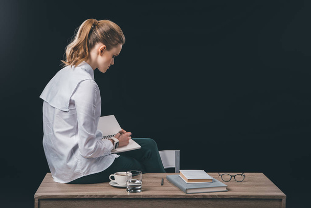 Woman sitting on table and making notes - Photo, Image