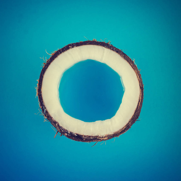 De helft van een rijpe kokosnoot met blauwe vloeistof  - Foto, afbeelding