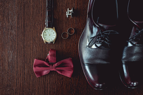 Close up de acessórios do homem moderno. alianças de casamento, laço de cereja, sapatos de couro, relógio e abotoaduras
 - Foto, Imagem
