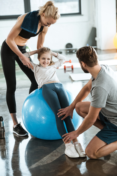 Cute gir exercising on swiss ball with parents - Foto, afbeelding