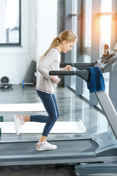 Blonde girl workout on treadmill, side view  - Zdjęcie, obraz
