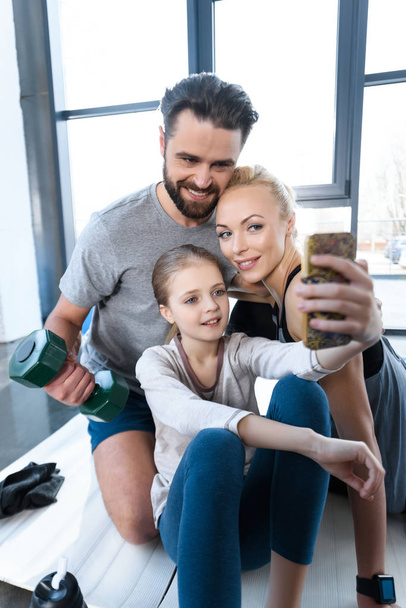 Dziewczyna biorąc autoportret z rodzicami w centrum fitness - Zdjęcie, obraz