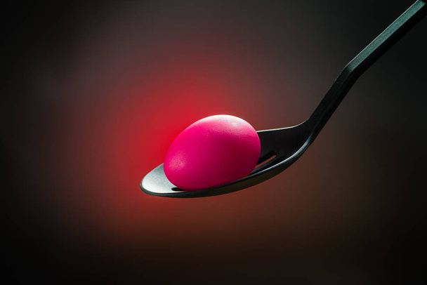 Pink Easter egg in a spoon in the centre a bright red spot on a  - Photo, image
