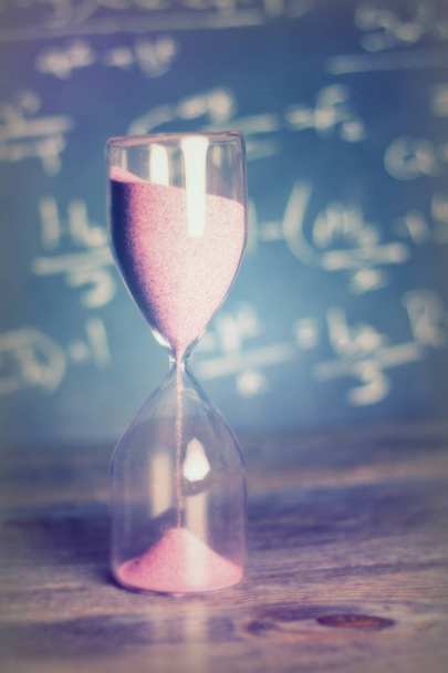 Hourglass on wood with a blackboard background - Photo, Image