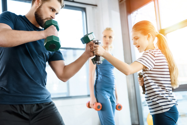 Happy family exercising with dumbbells at fitness studio - Fotoğraf, Görsel