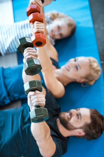 Happy family exercising with dumbbells at fitness studio - Фото, изображение