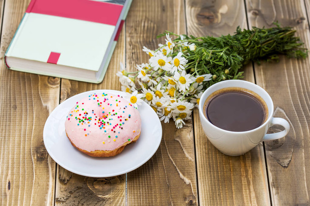 Tasse schwarzen Kaffee mit rosa Donut auf einem Teller - Foto, Bild