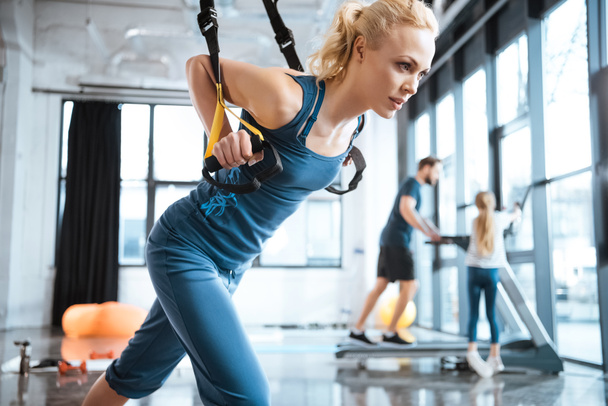 Blonde fitness woman training with trx fitness straps - Фото, зображення