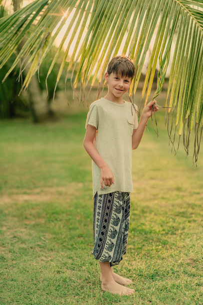 the boy on the green grass holding a palm branch - Фото, зображення