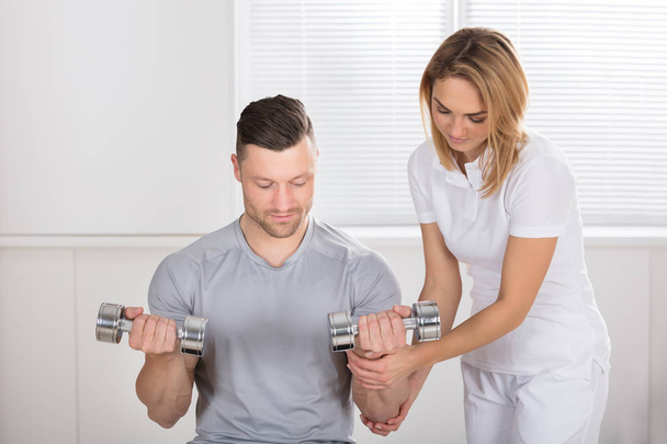 Fyzioterapeut pomůže muž na cvičení - Fotografie, Obrázek