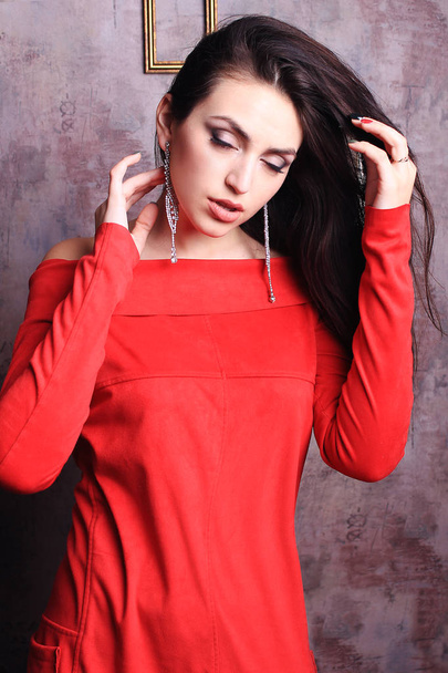 Beautiful girl in red dress straightens her hair. - Foto, Imagem