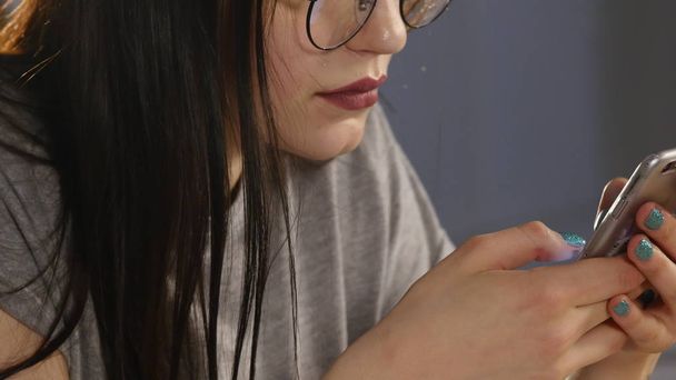 Young woman with glasses browsing photos on smartphone. reflected in the glasses - Foto, Imagen