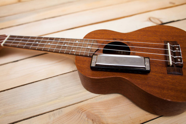 木製の背景にハワイの 4 弦ウクレレ ギターと鉄ハーモニカー - 写真・画像