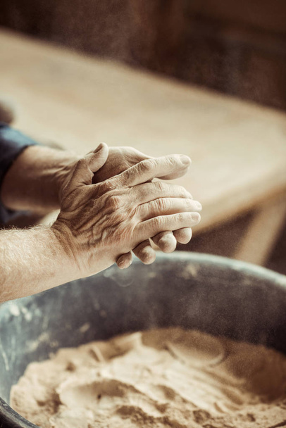 Close up van mannelijke potter handen nemen klei uit een kom - Foto, afbeelding