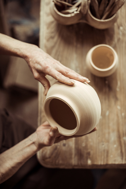 Close up of female hands examining ceramic bowl at workshop - Photo, Image