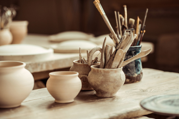 Primer plano de pinceles con herramientas de cerámica en cuencos sobre mesa
 - Foto, Imagen
