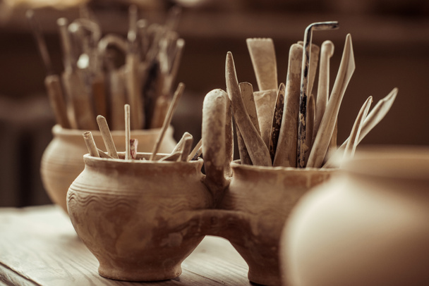 Close up van verf penselen met aardewerk tools in kommen op tafel - Foto, afbeelding