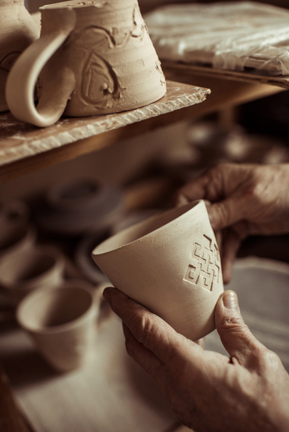 Primer plano de la mano masculina del alfarero examinando taza de arcilla
 - Foto, Imagen