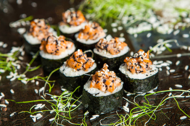Různé druhy sushi Jídlo podávané na černém pozadí. Zblízka chutné čerstvé sushi rolls ryb s rýží na desce. Suši válce sloužil na dřevěnou desku v restauraci - Fotografie, Obrázek