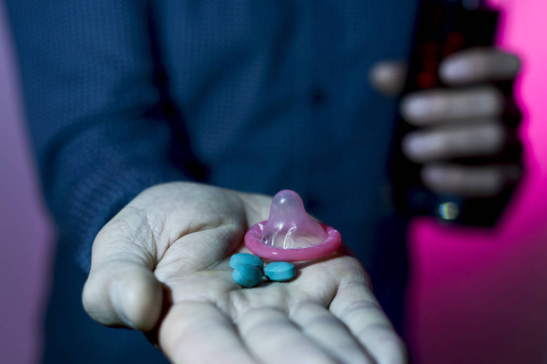 homem com bebida mista, comprimidos azuis e preservativo
 - Foto, Imagem