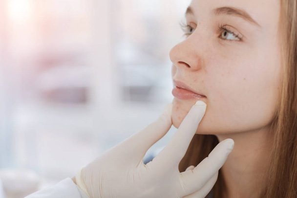 Proficient dermatologist examining patient face in the clinic - Foto, imagen