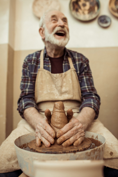 Front view of male craftsman working on potters wheel - Foto, afbeelding